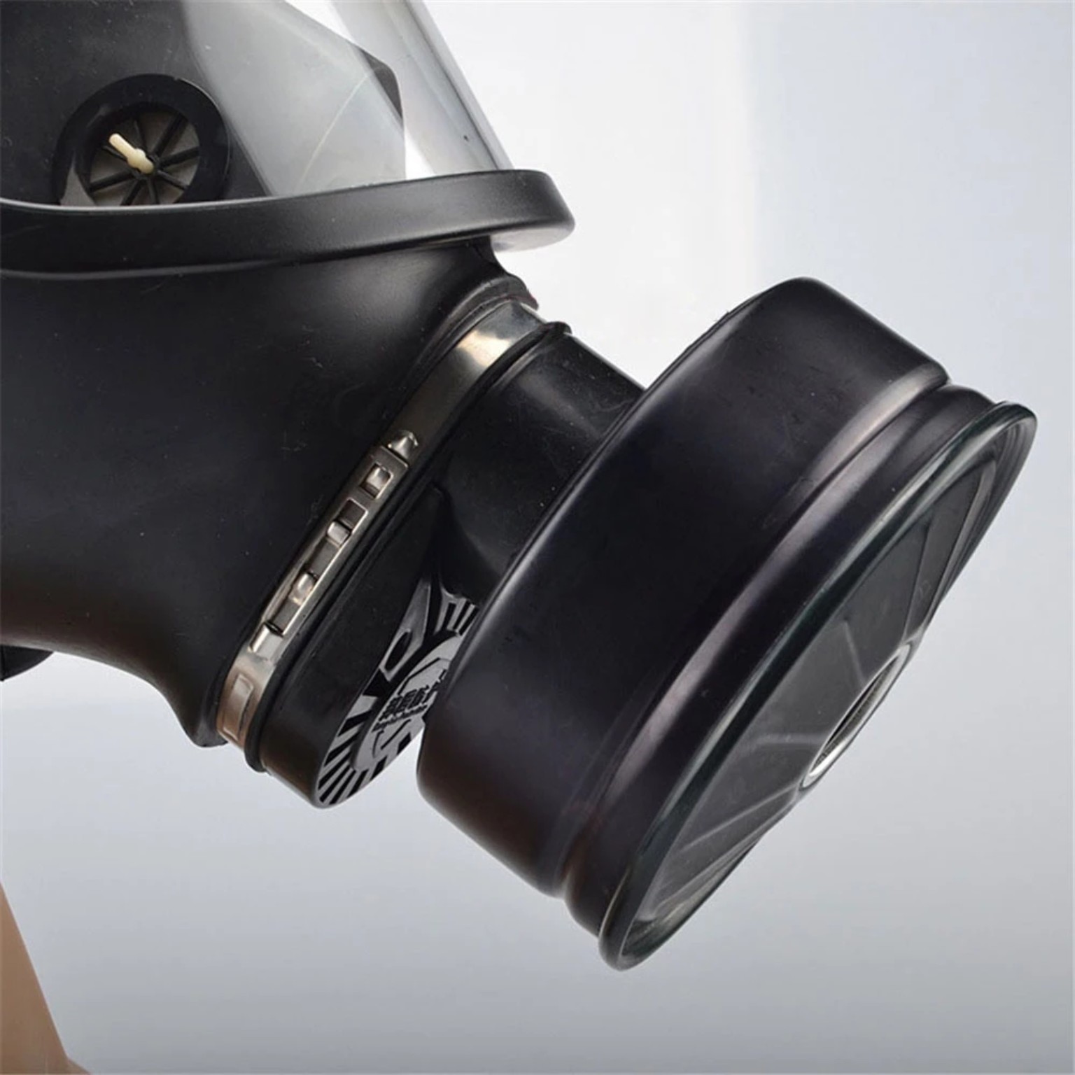 Close-up of the respirator's black cartridge or canister connection and retaining ring.